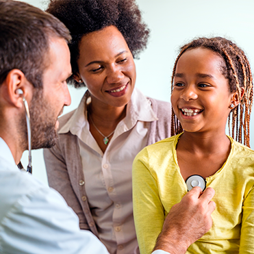 Médico consultando criança, acompanhada pela mãe